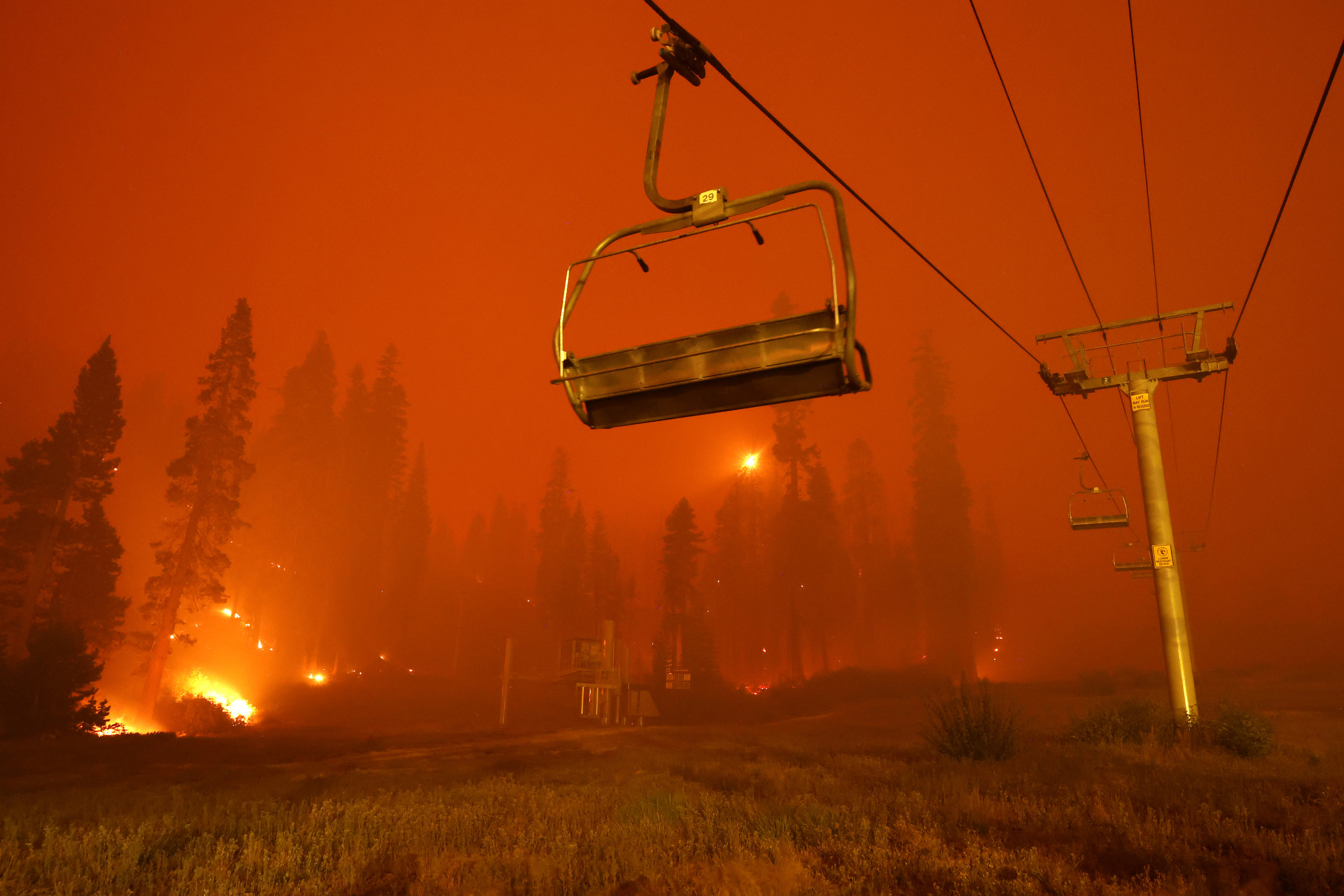 A ski lift with a giant wildfire behind it 