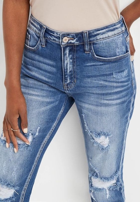 An image of a model wearing a pair of high-rise medium ripped boyfriend jeans