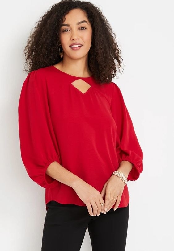 An image of a model wearing a keyhole neck balloon sleeve blouse in red