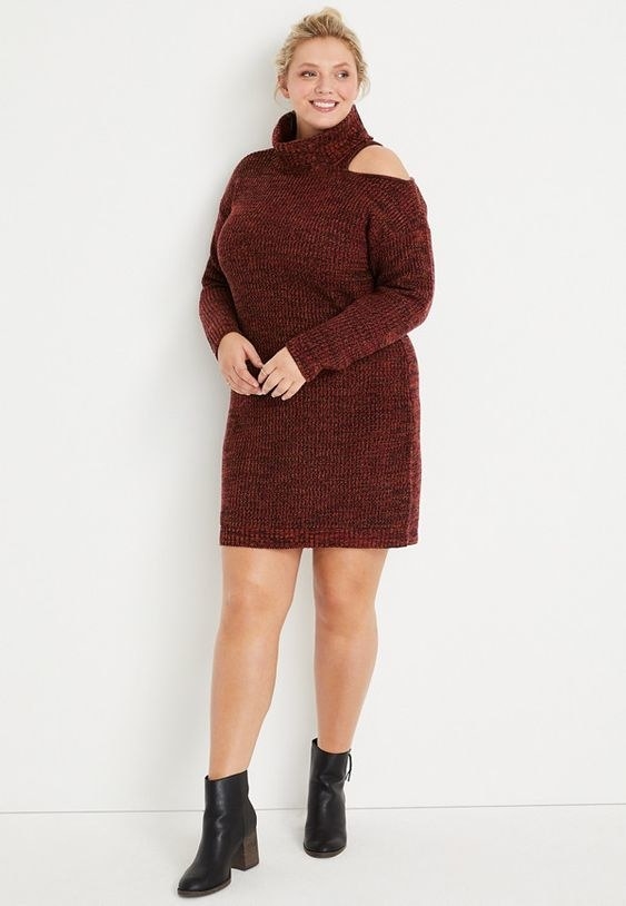 An image of a model wearing a plus-size red cut out turtle neck sweater dress