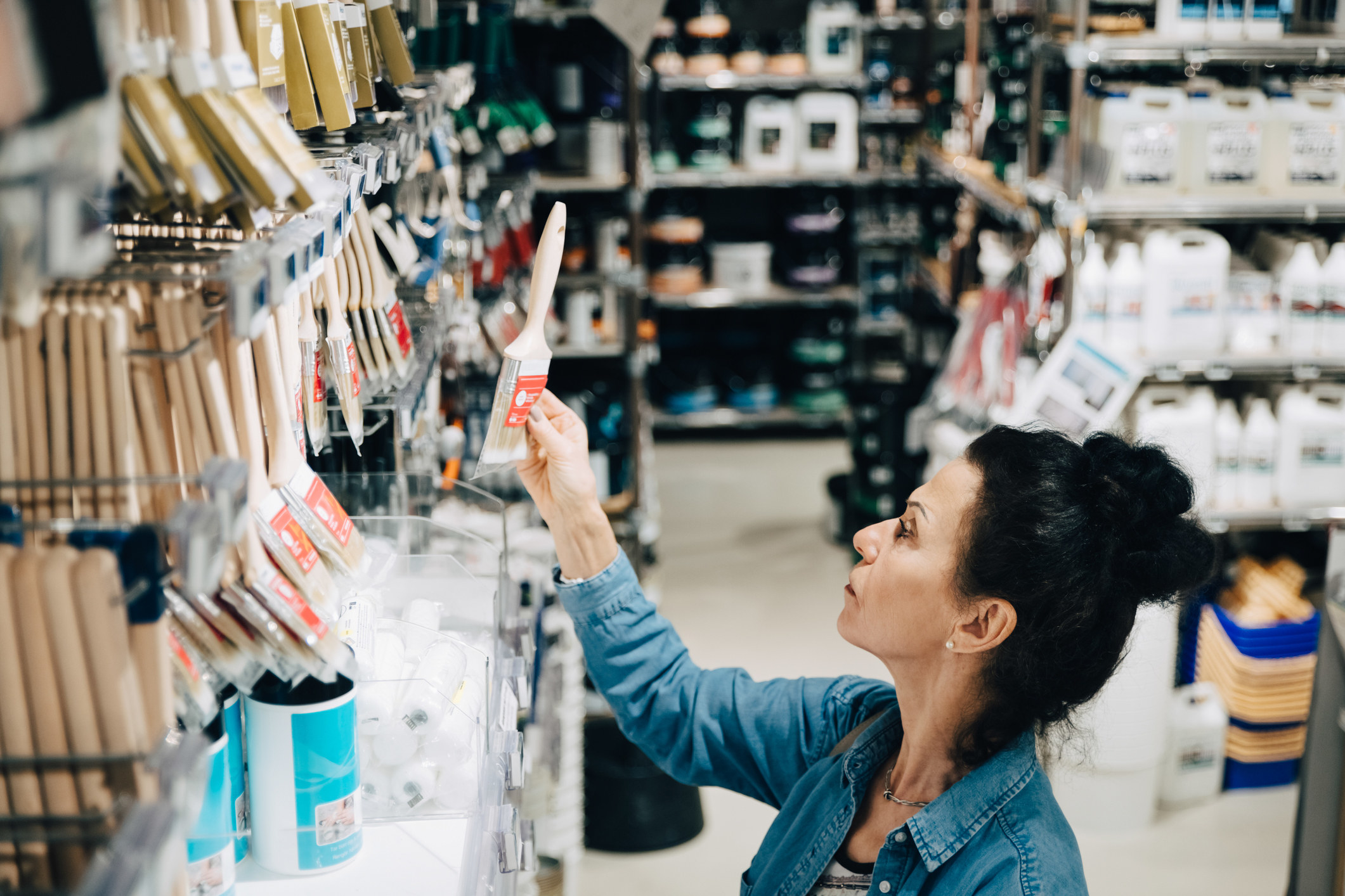 A woman looking at paintbrushes at the hardware store