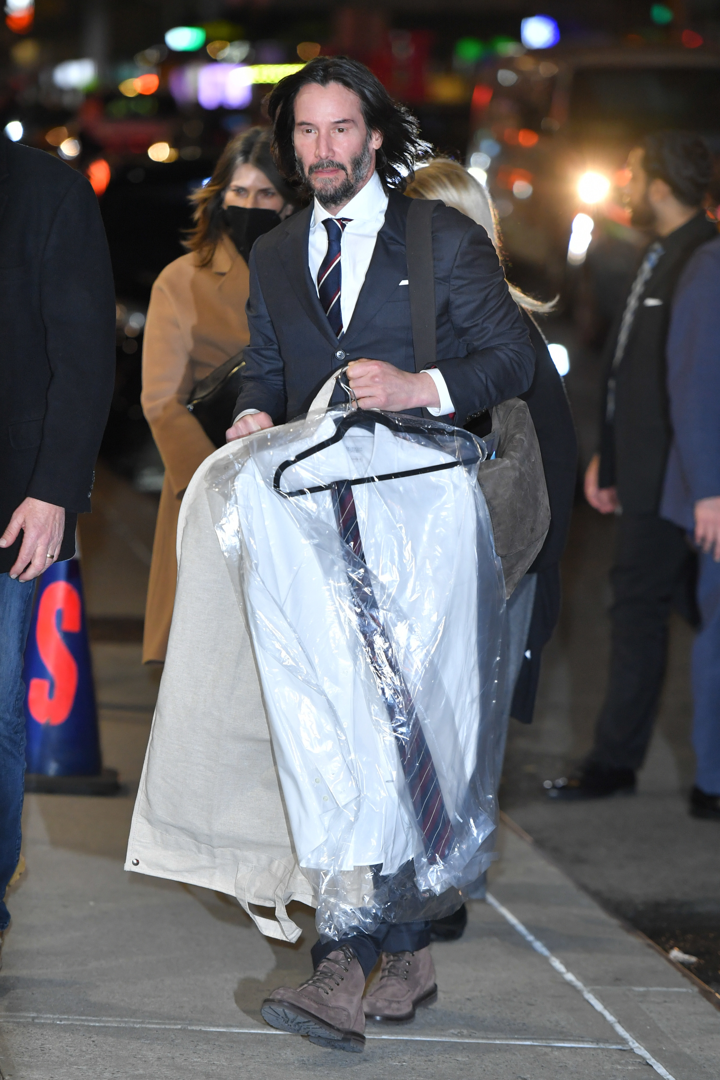 Reeves walks down the street with drycleaning
