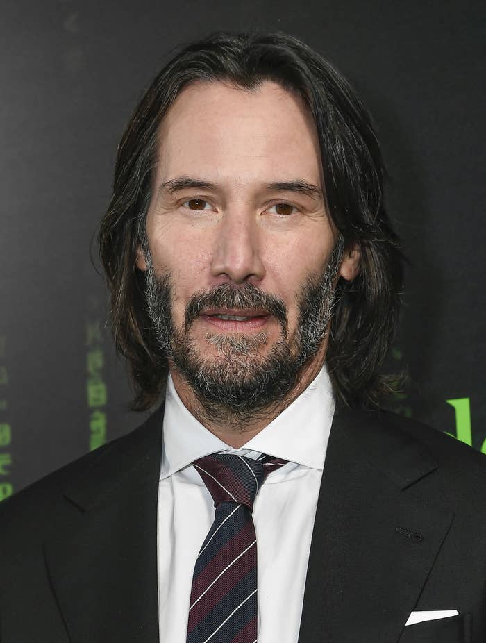 Keanu Reeves looks at the camera while wearing a suit