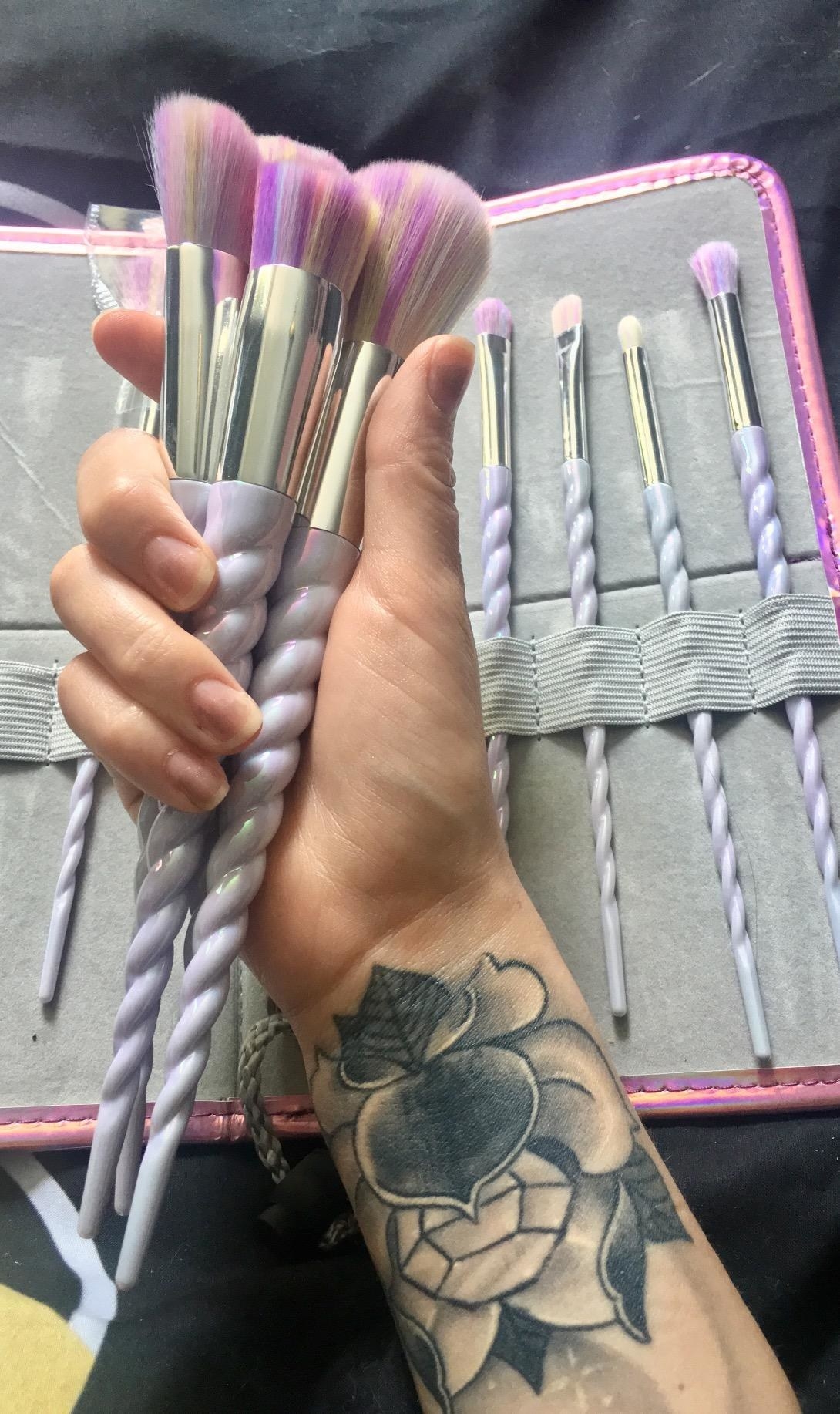 a reviewer shows the set of makeup brushes with purple handles that look like unicorn horns