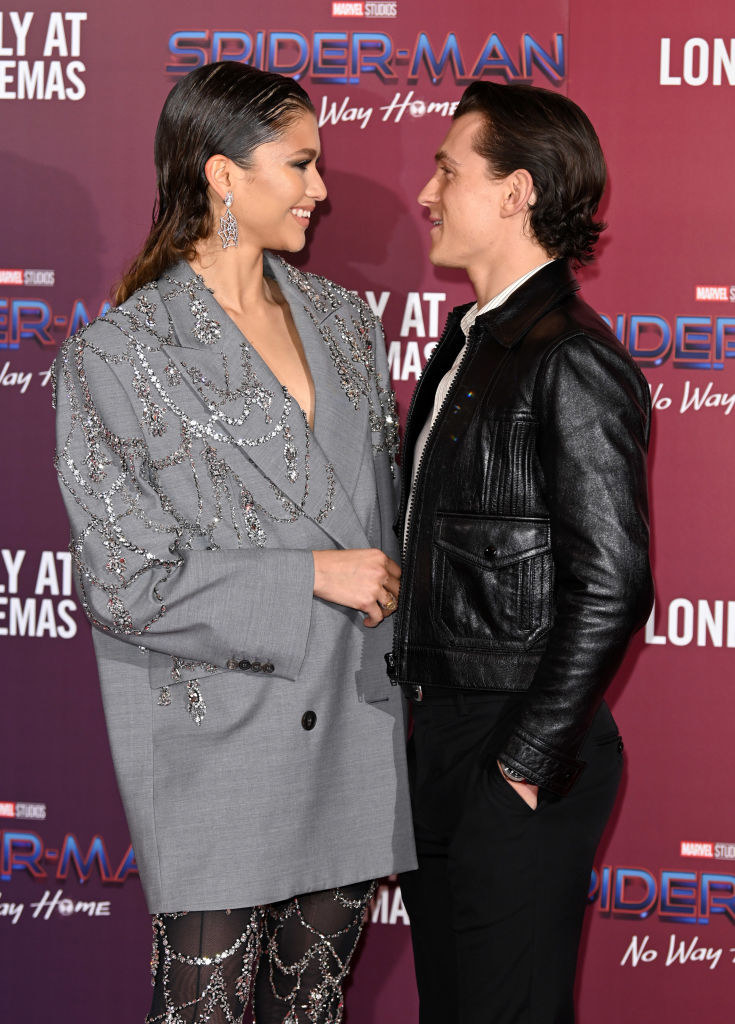 Zendaya and Tom Holland gazing at each other and smiling during their couple-red carpet debut for Spider-Man: No Way Home premiere