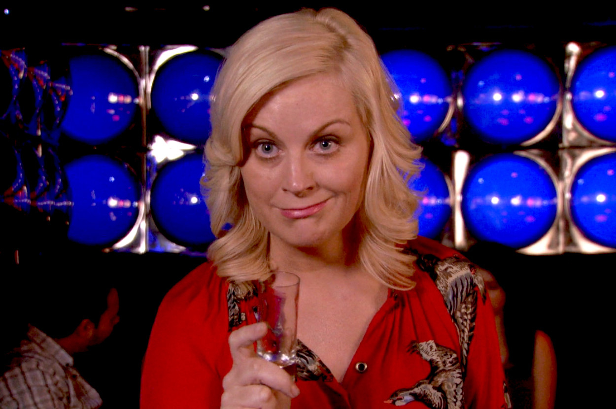 Amy Poehler as Leslie holds a drink and looks inebriated in a still from Parks and Rec