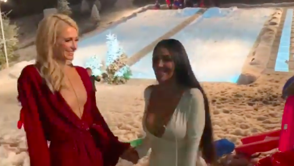 Kim and Paris Hilton smiling as they stand on the sledding hill