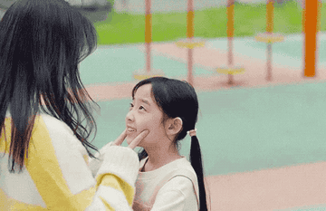 a mother playing with her daughter when a man comes up and puts his arms around her