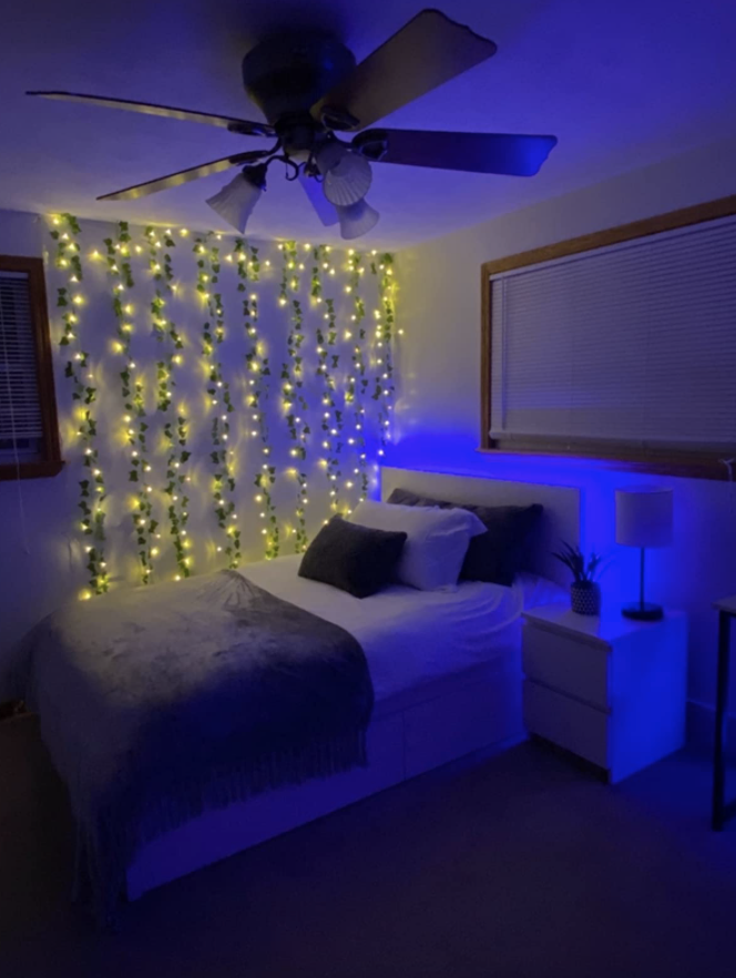 bedroom with fake vines that have string lights attached to them hung up on a wall