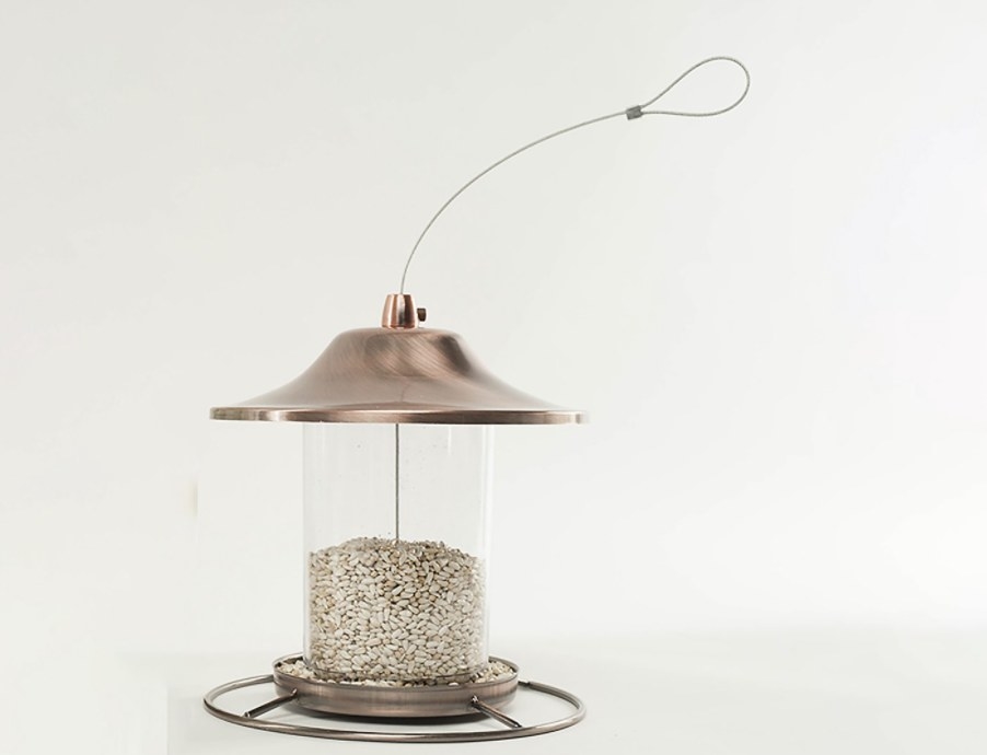 A brown bird feeder with tan birdseed in it