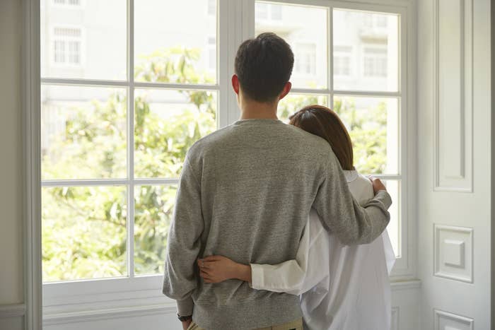 A couple looking out the window holding each other