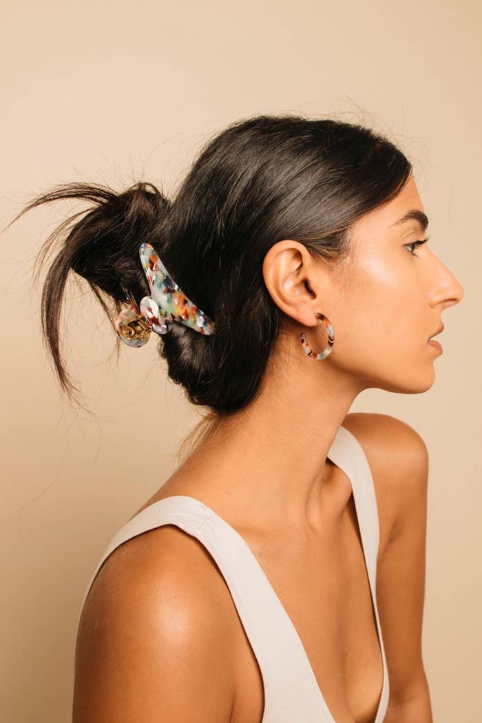 model wears colorful speckled claw clip in half-up hair style