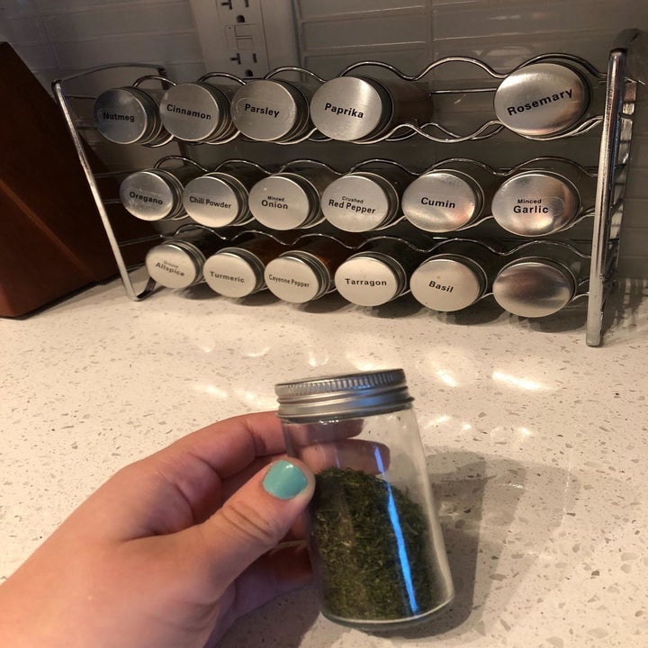 A reviewer holding a spice bottle with the rack in the background