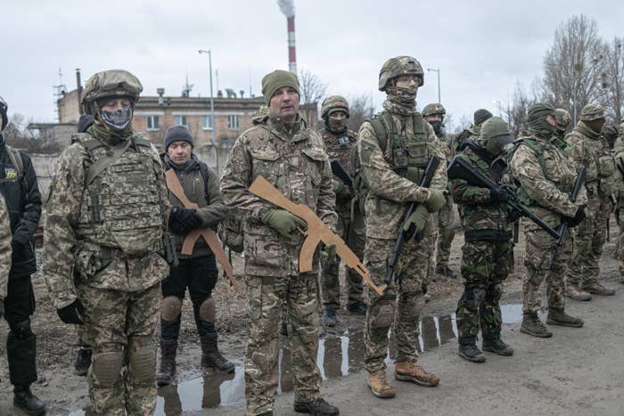 A row of reservists in fatigues with airsoft guns and gun cutouts