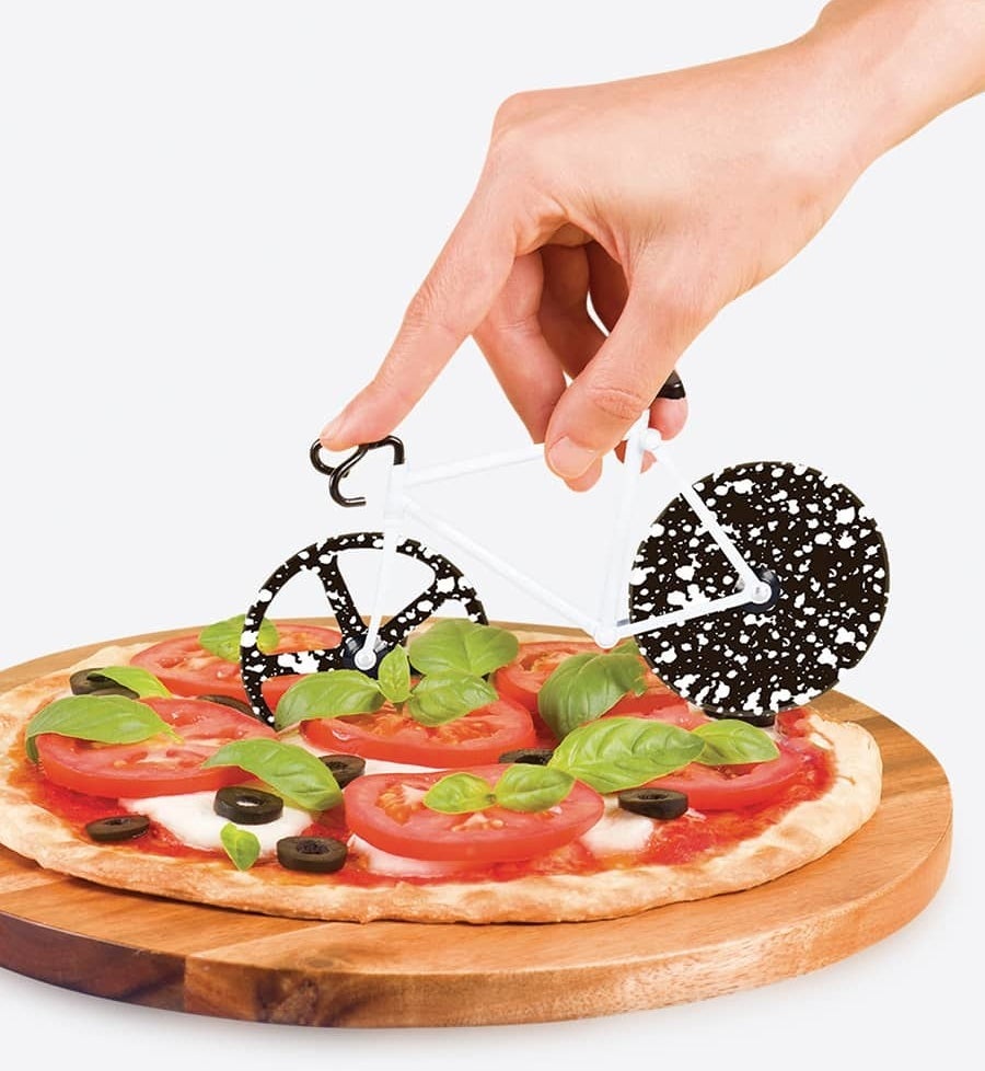 the black and white pizza cutter cutting into a thin pizza