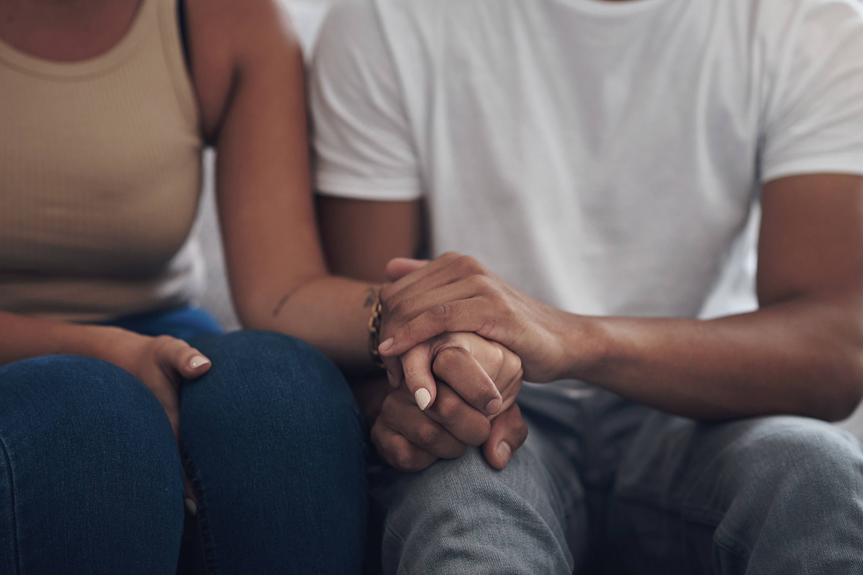 Two people sitting down and holding each other&#x27;s hand