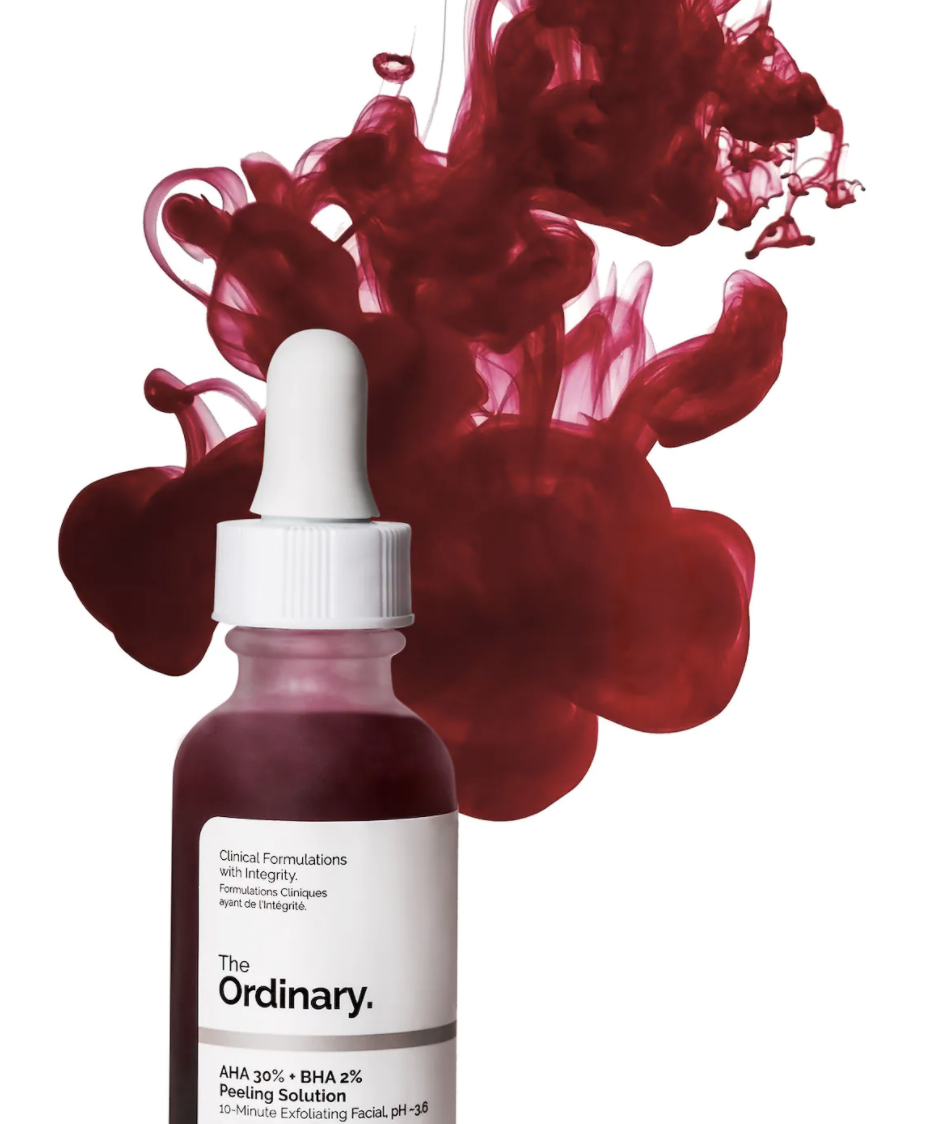 bottle of the The Ordinary peeling solution above surrounded by dark red formula