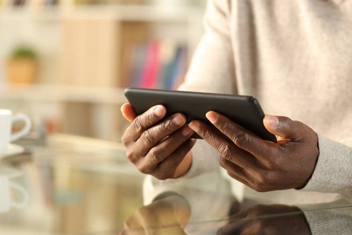 A person holding a smartphone horizontally as the sit in front of a glass table