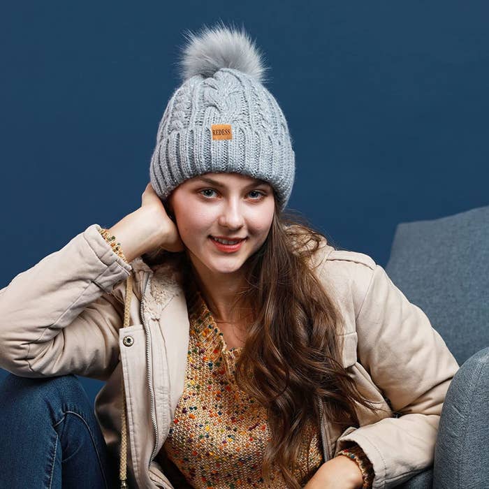 A person wearing a thick knit beanie on their head