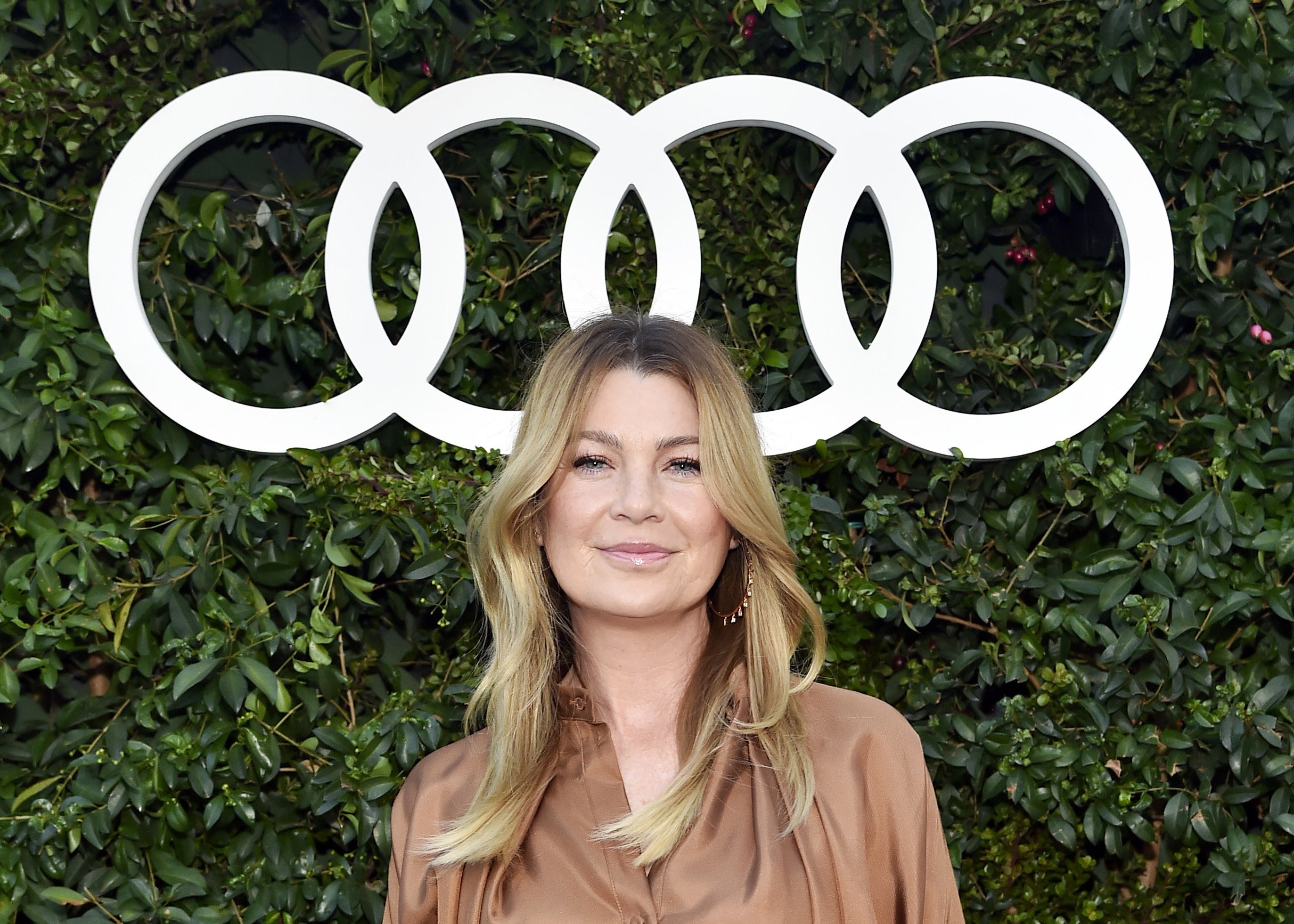 Photo of Ellen Pompeo standing in front of bushes