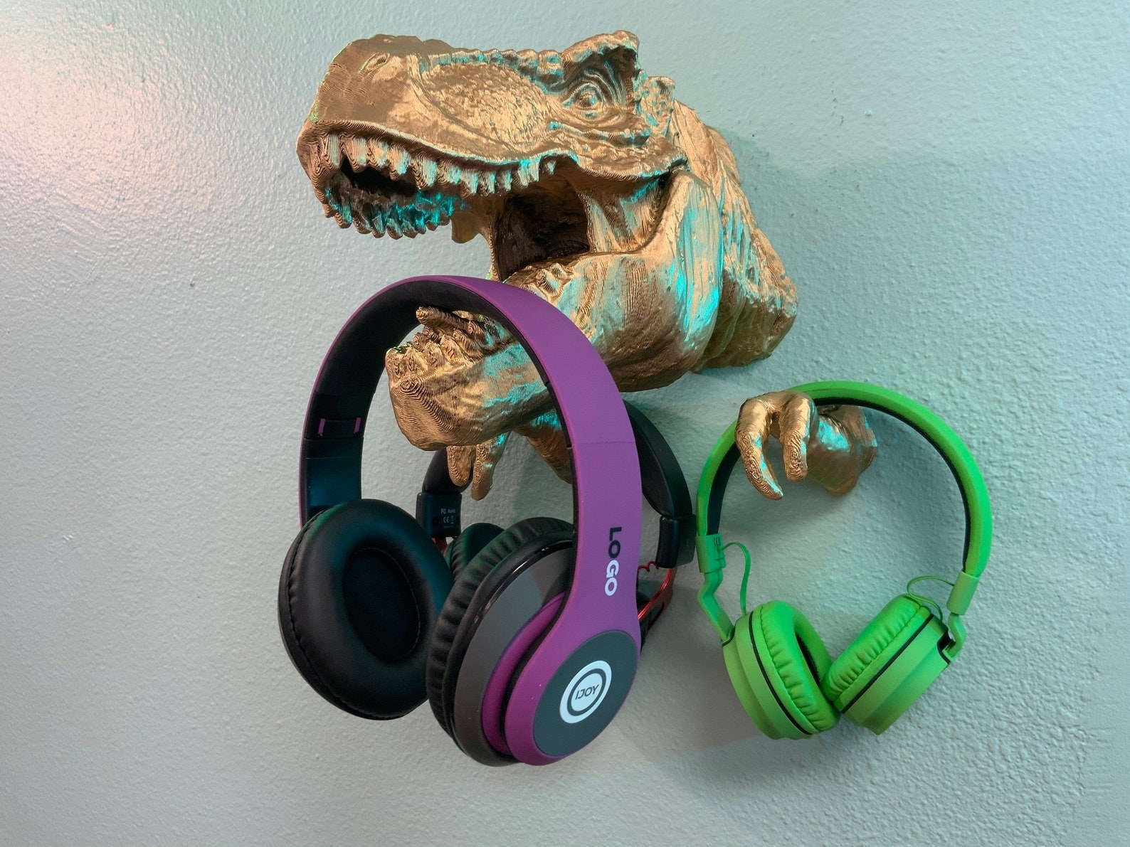 metallic gold T-rex 3D mounted on wall with headphones handing from its mouth
