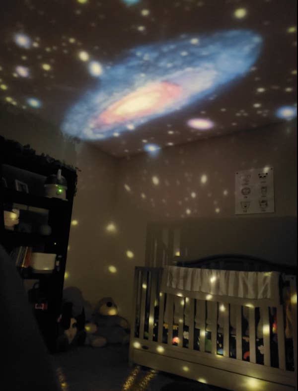 reviewer&#x27;s pic of a nursery with the stars and planets projected with light on the ceiling