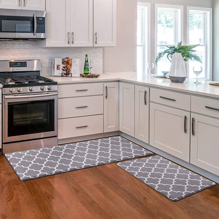 two gray kitchen mats with a white design on them