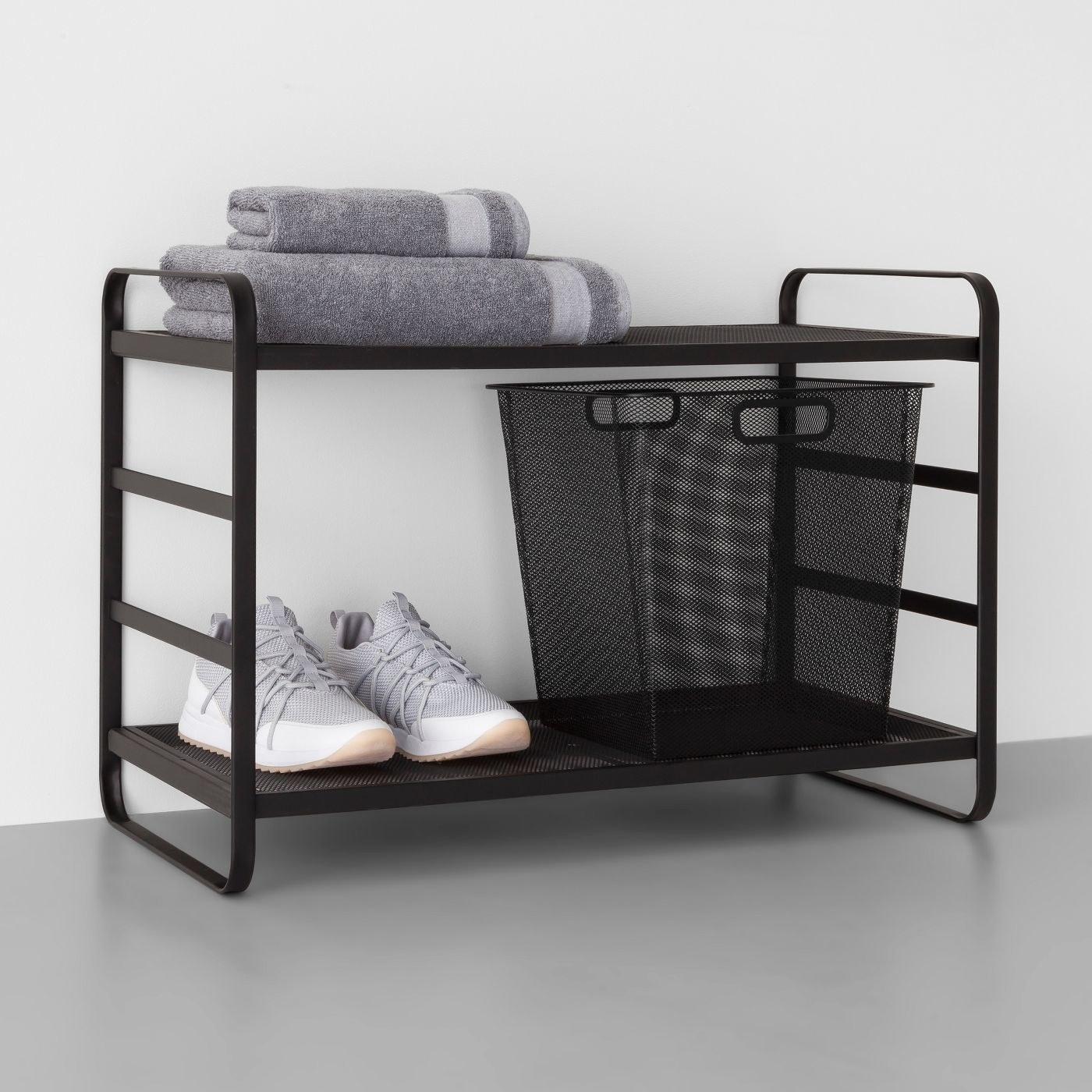 the black mesh rack with shoes and a towel