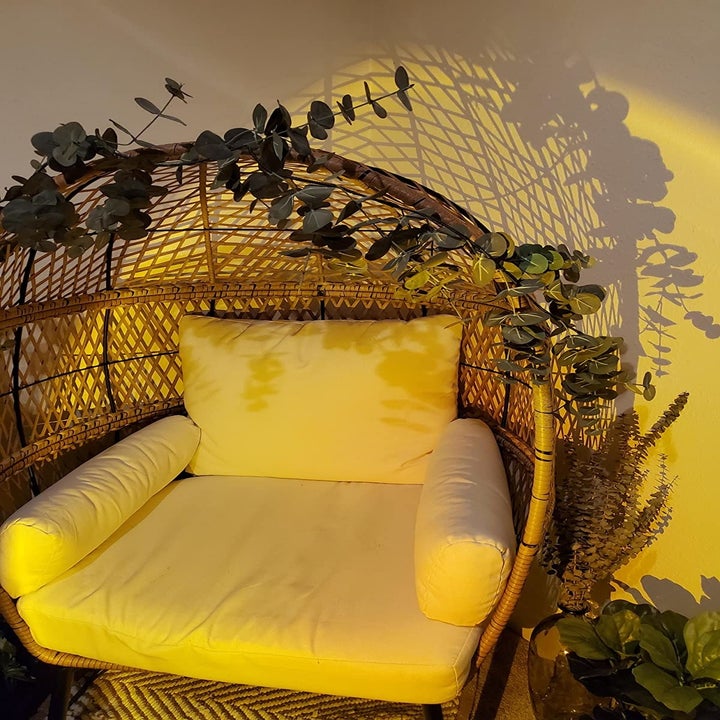 reviewer image of the lamp shining on their wicker furniture