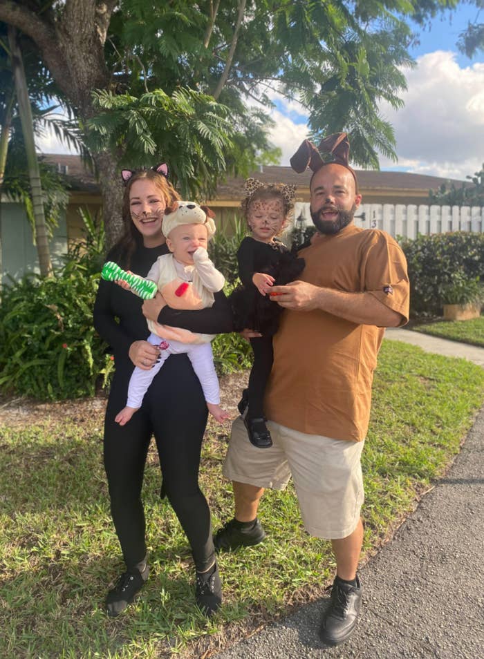 The couple standing outside dressed up in costumes and holding their kids