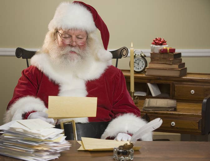 A bespectacled Santa Claus holding a letter addressed to him