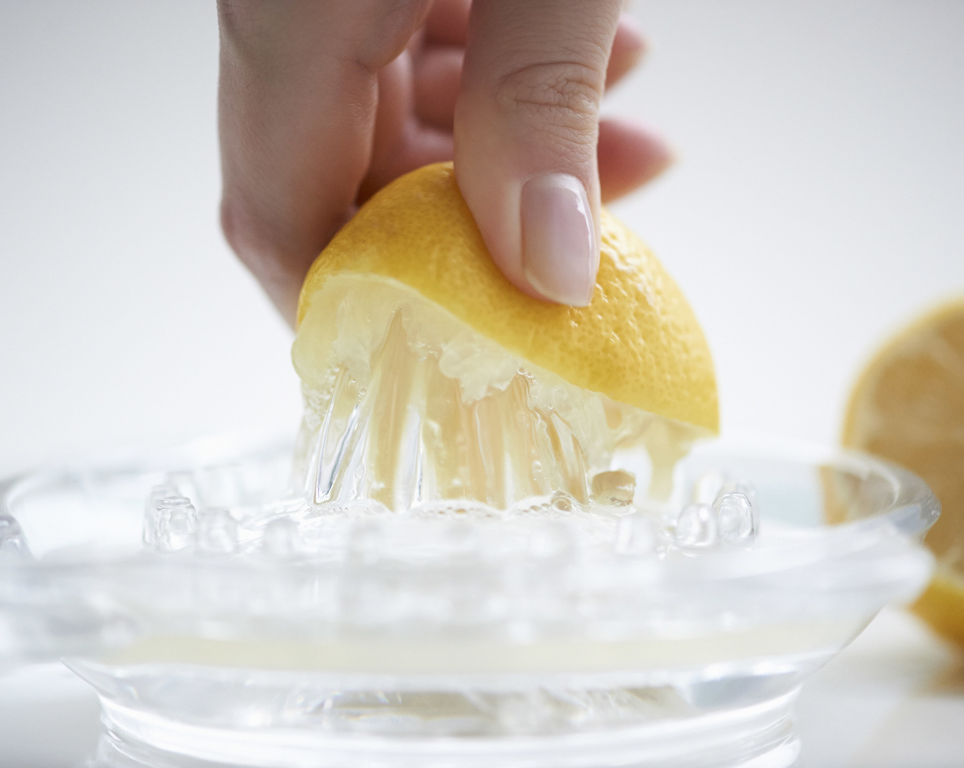 Close up of a female hand pressing a lemon half onto a juicer.