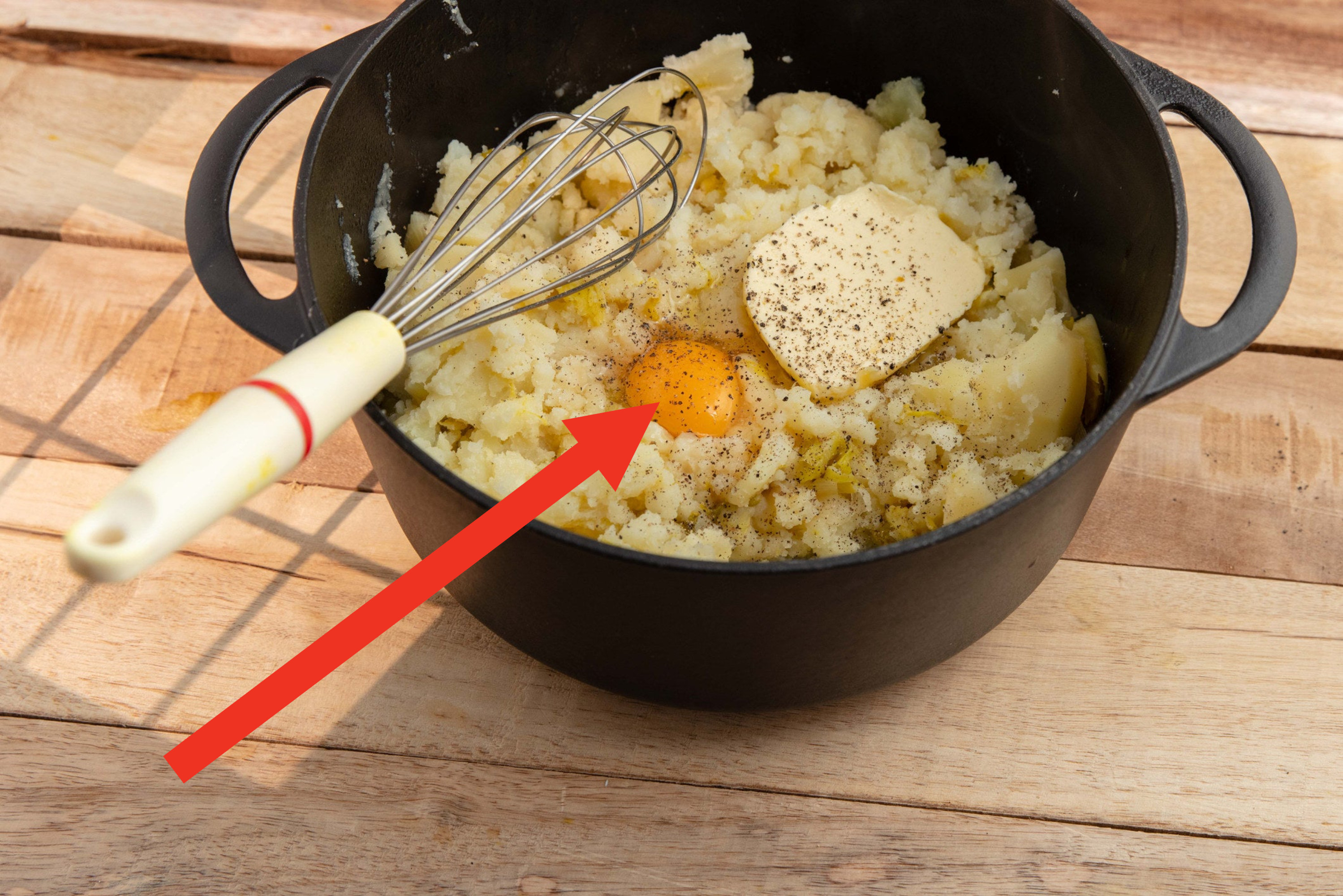 An egg and butter in a pot of mashed potatoes.