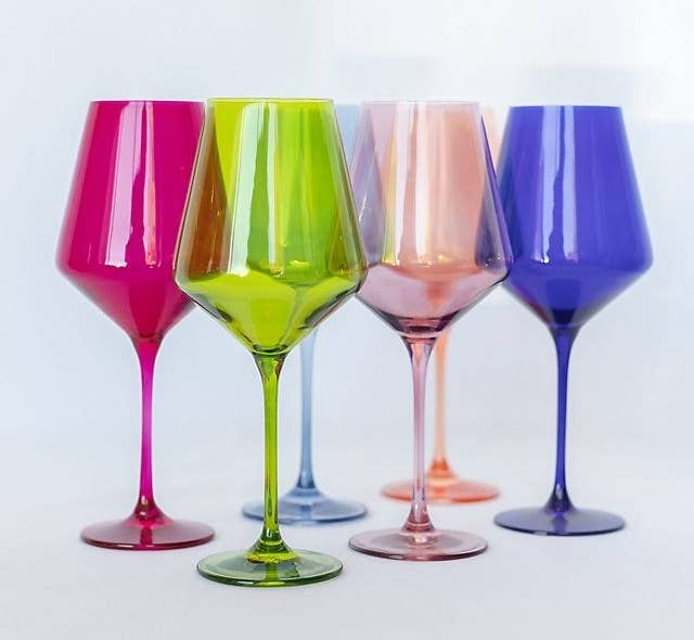 Six wine glasses; one in blue, purple, orange, green, yellow, and pink