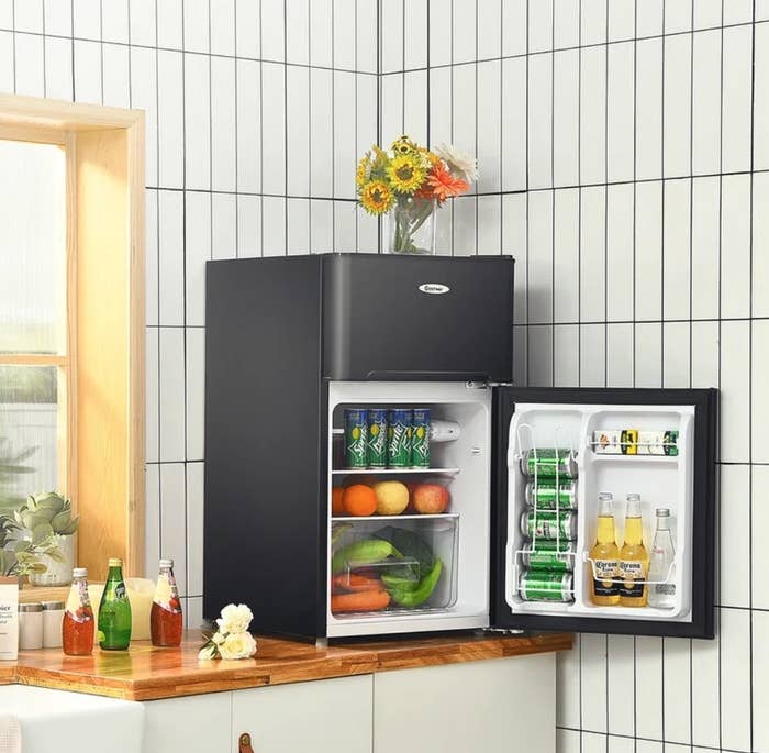 A black mini fridge with a freezer compartment atop