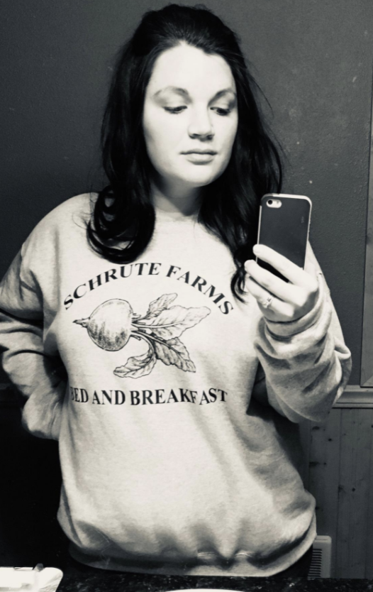 reviewer wearing a The Office sweatshirt with Schrute Farms Bed and Breakfast on it