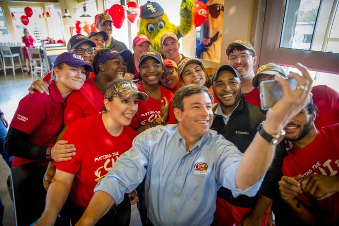 A group of Raising Cane&#x27;s employees smiling and taking a selfie.