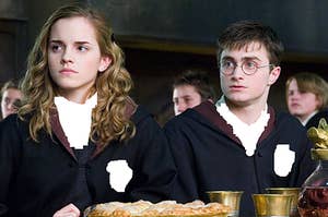 Hermione Granger sits next to Harry Potter as they sit in the Great Hall