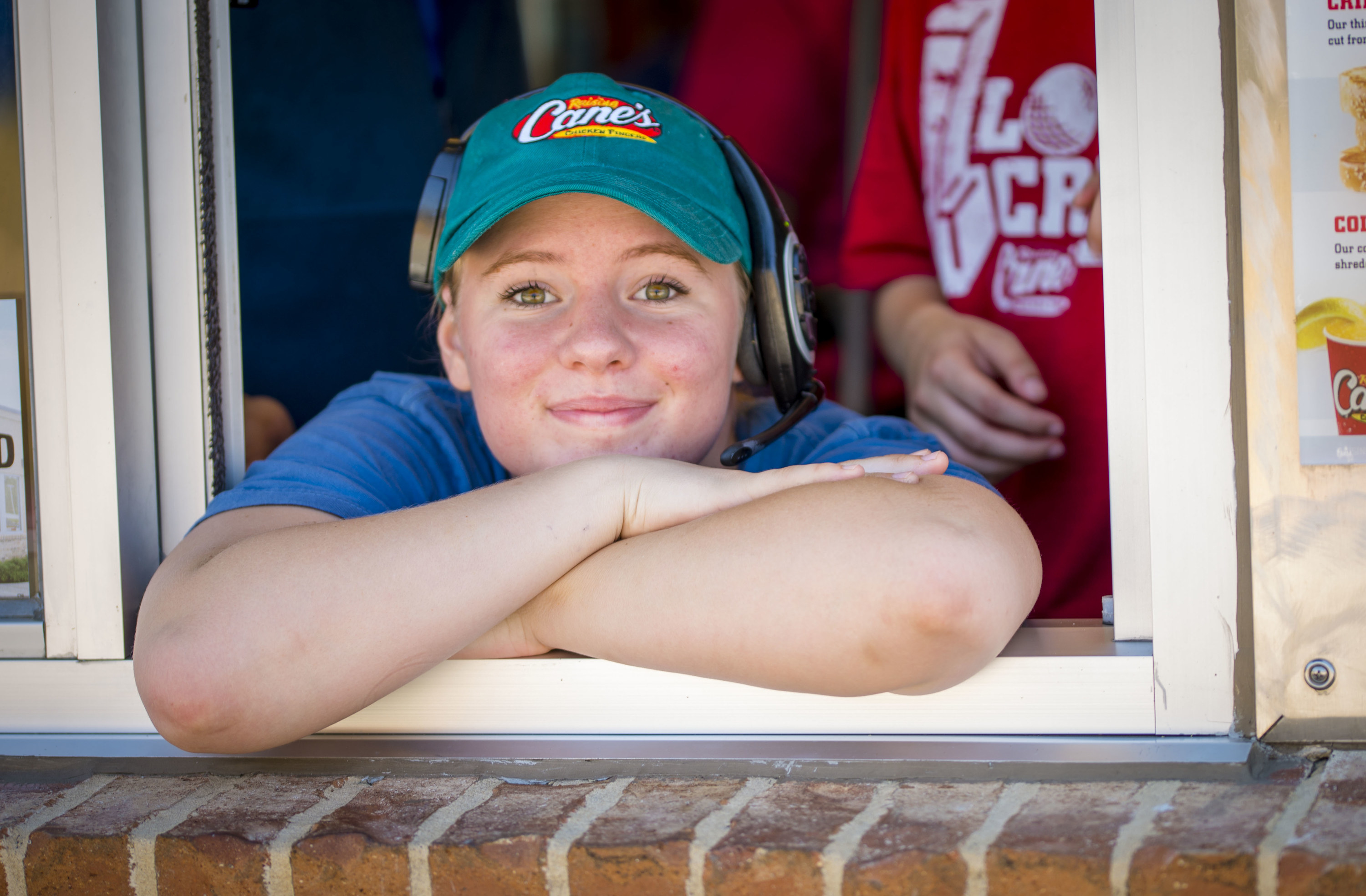 A Raising Cane&#x27;s employee smiling in the take out window.