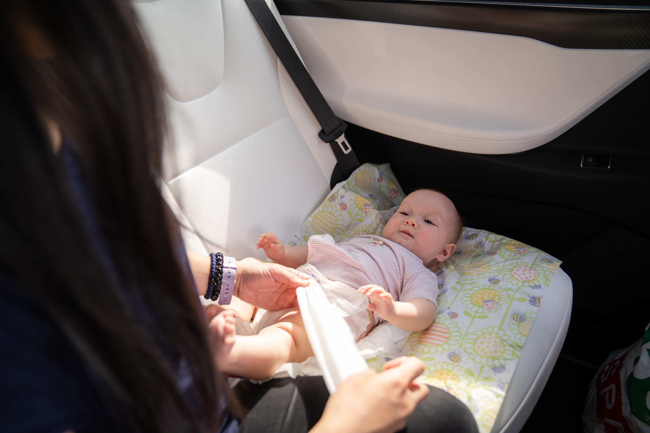 Someone changes a baby&#x27;s diaper in a car