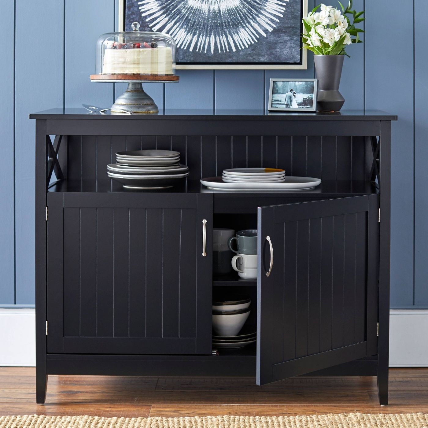 A black lined buffet table with open drawers that show mugs and plates.