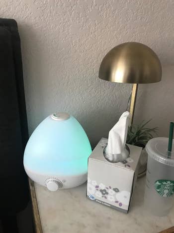 reviewer photo of humidifier glowing blue on a bedside table
