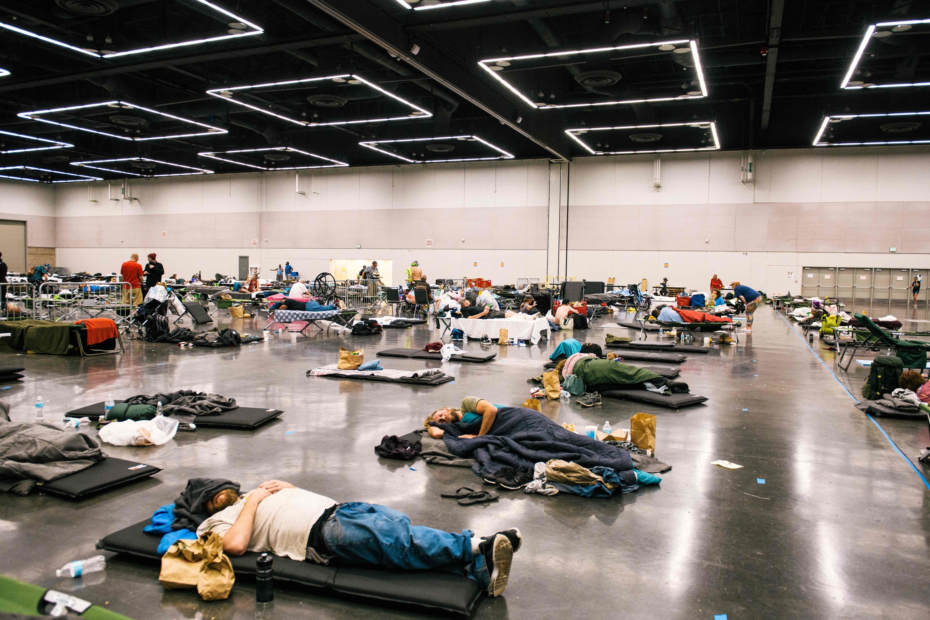 people sleep on air mats on the floor of a convention center in oregon