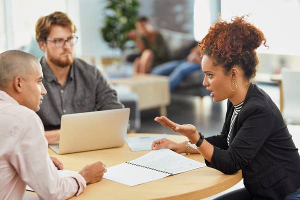 An woman asking a male colleague a question