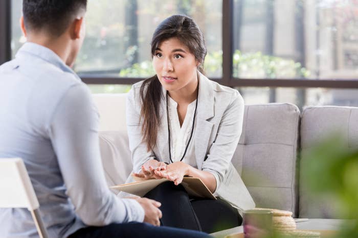 A woman sitting on a couch talking to a man in a serious conversation