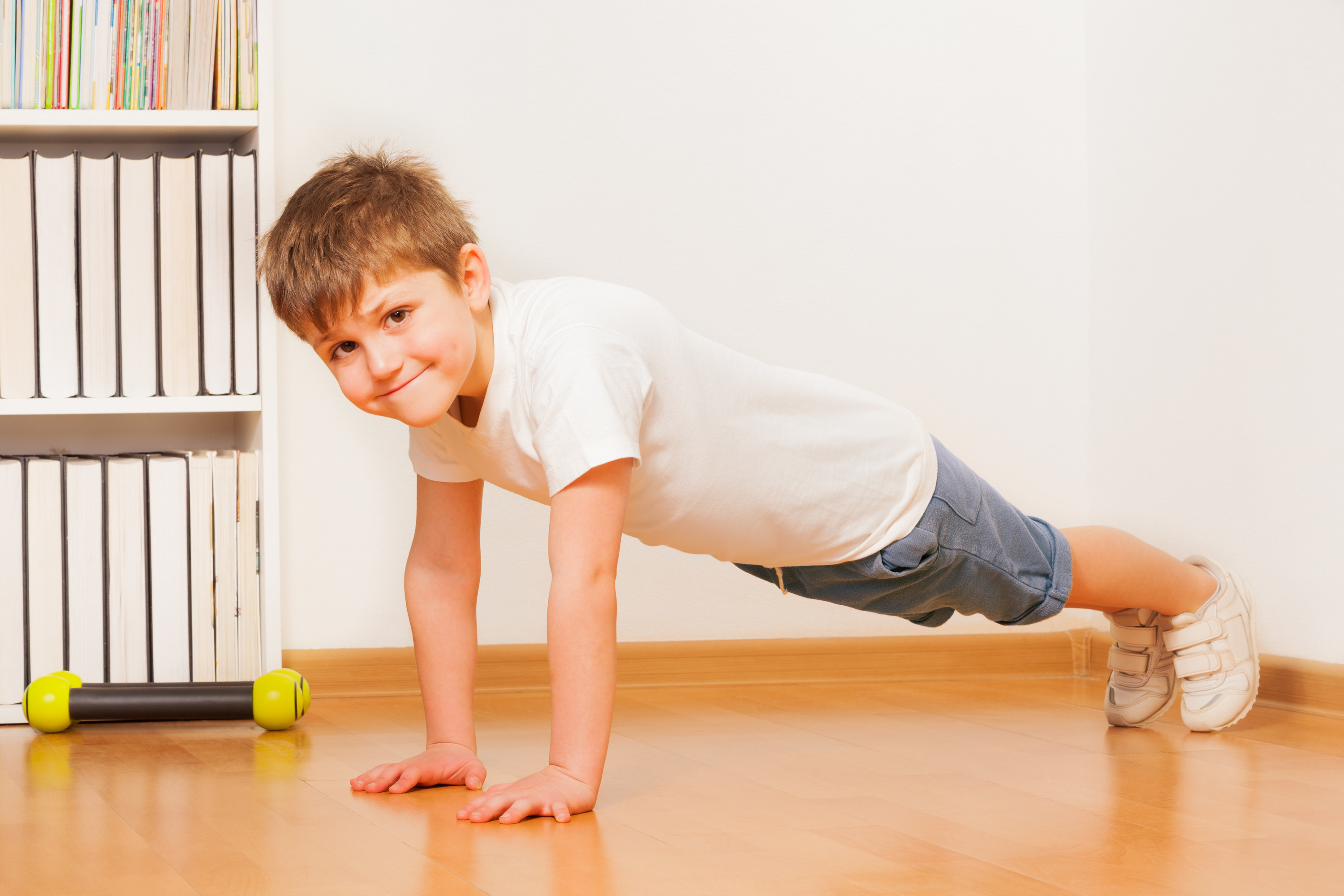 Young boy doing push ups with a forced smile
