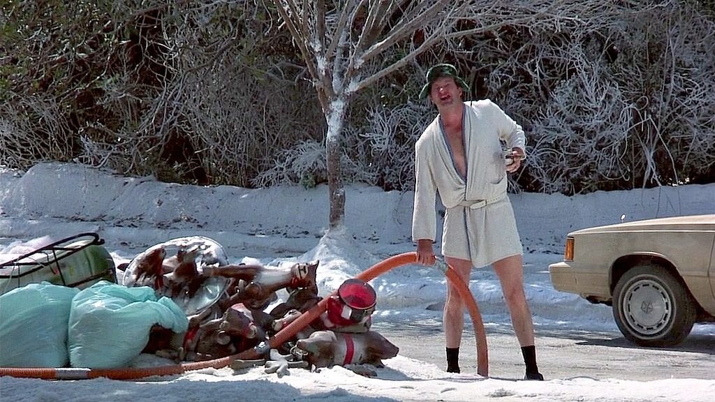 cousin eddie standing out in the snow next to the christmas decorations in national lampoon christmas vacation