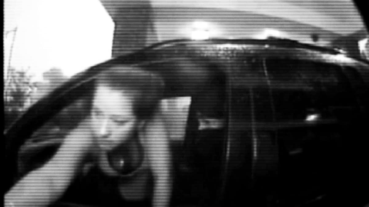 Video camera footage of a woman leaning out of her car