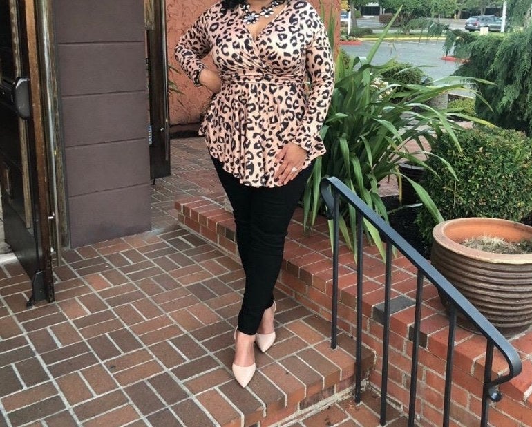 A reviewer wearing an animal print top, black pants and white shoes
