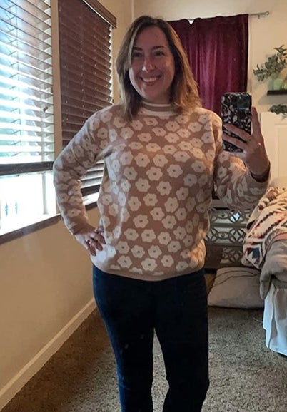 A reviewer wearing a brown floral top with jeans